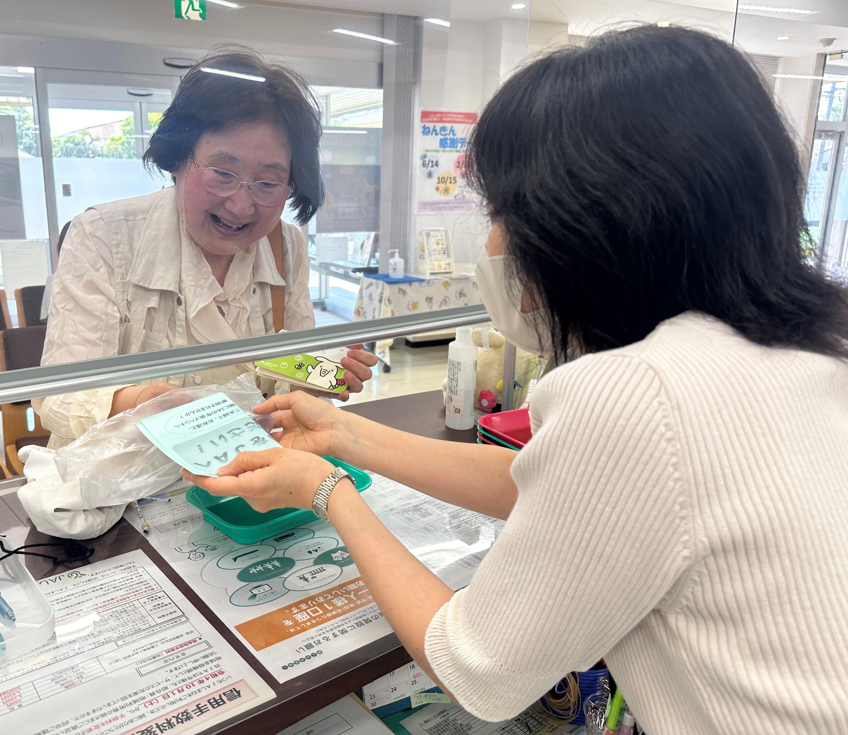 プレゼントと一緒にご案内を受ける来店者(津田支店).jpeg