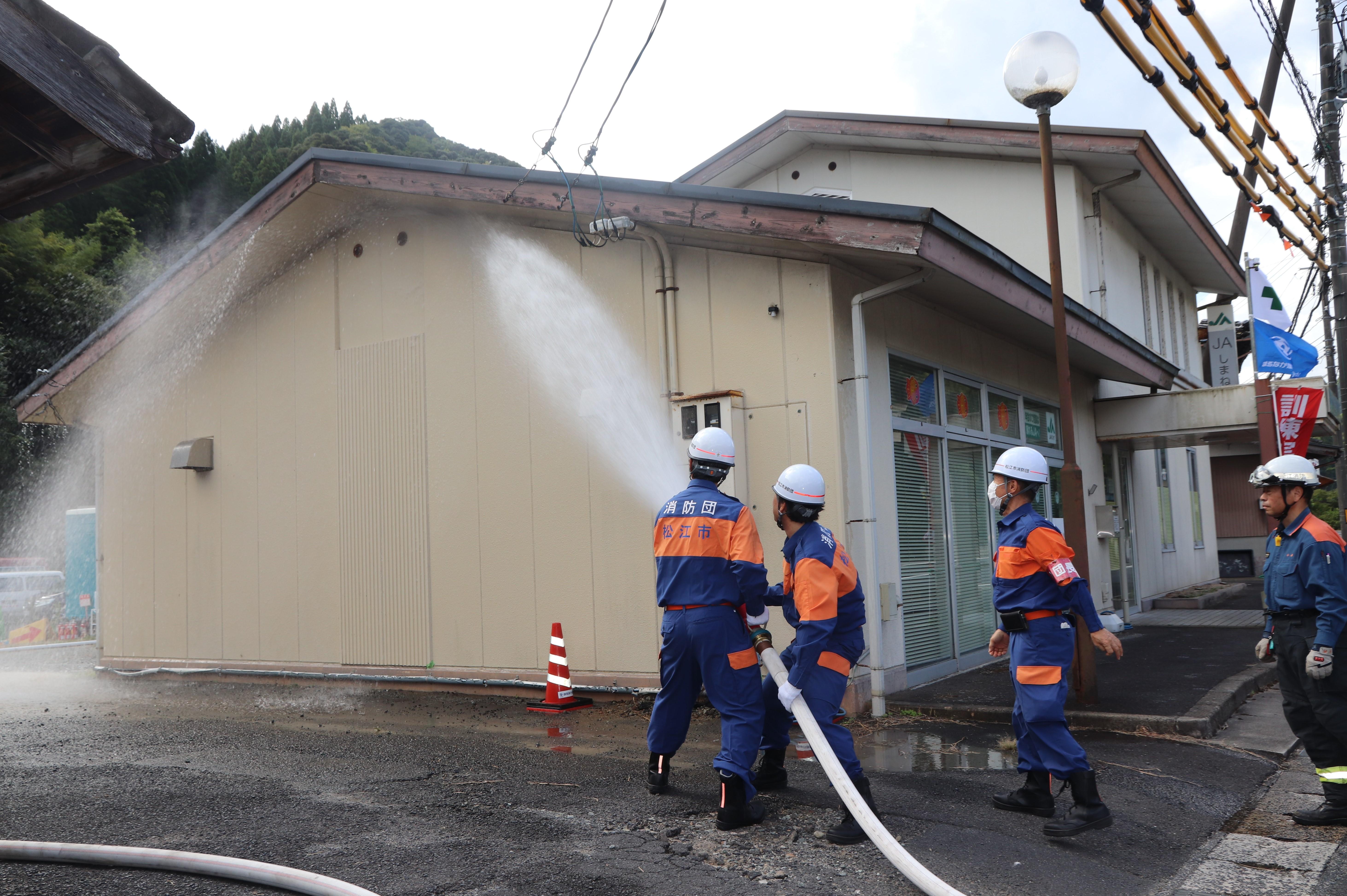 旧熊野店の壁に向かって放水する消防団員.JPG