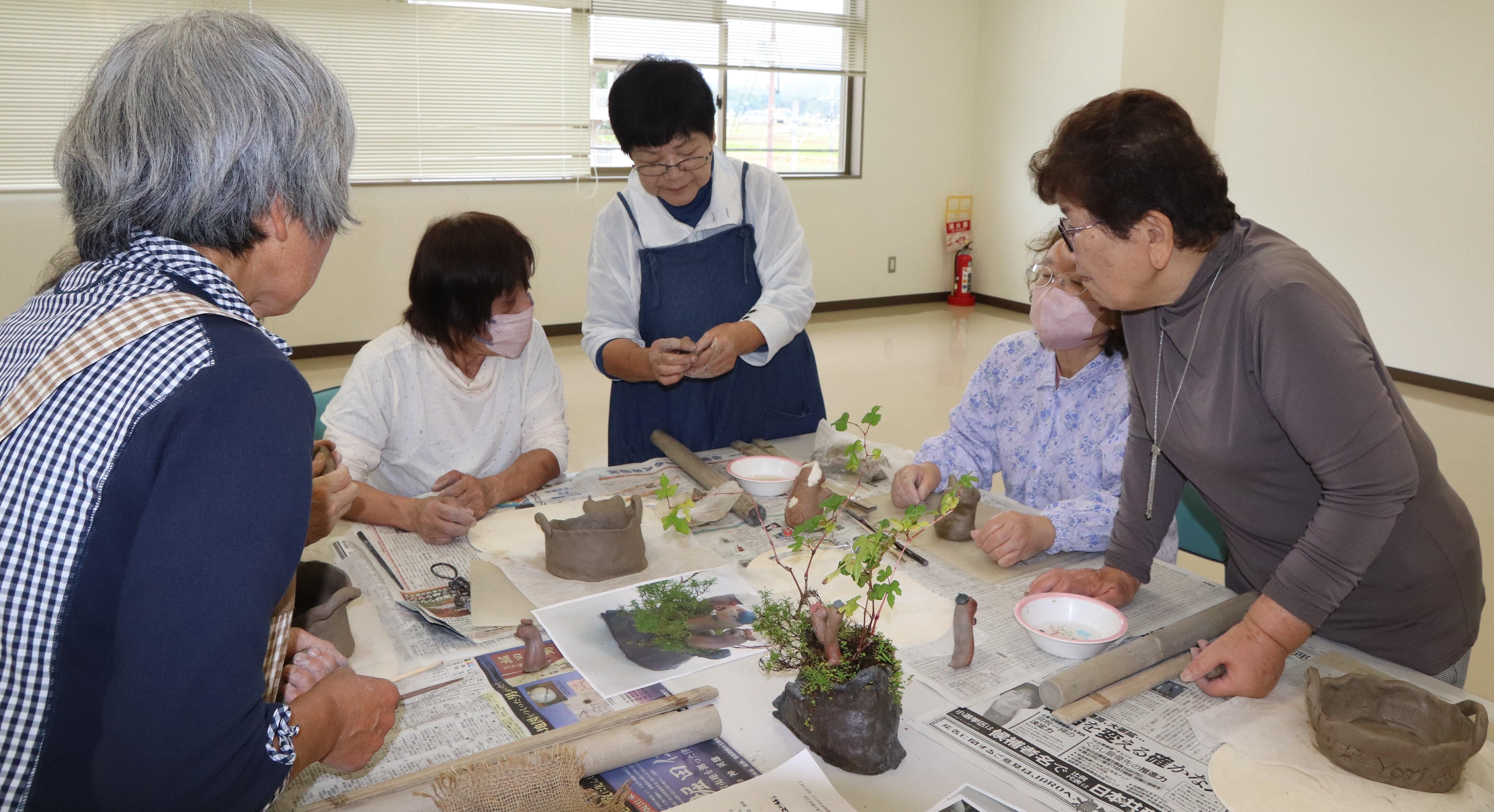 粘土の扱い方を説明する井上氏と熱心に話を聞く女性部員.JPG