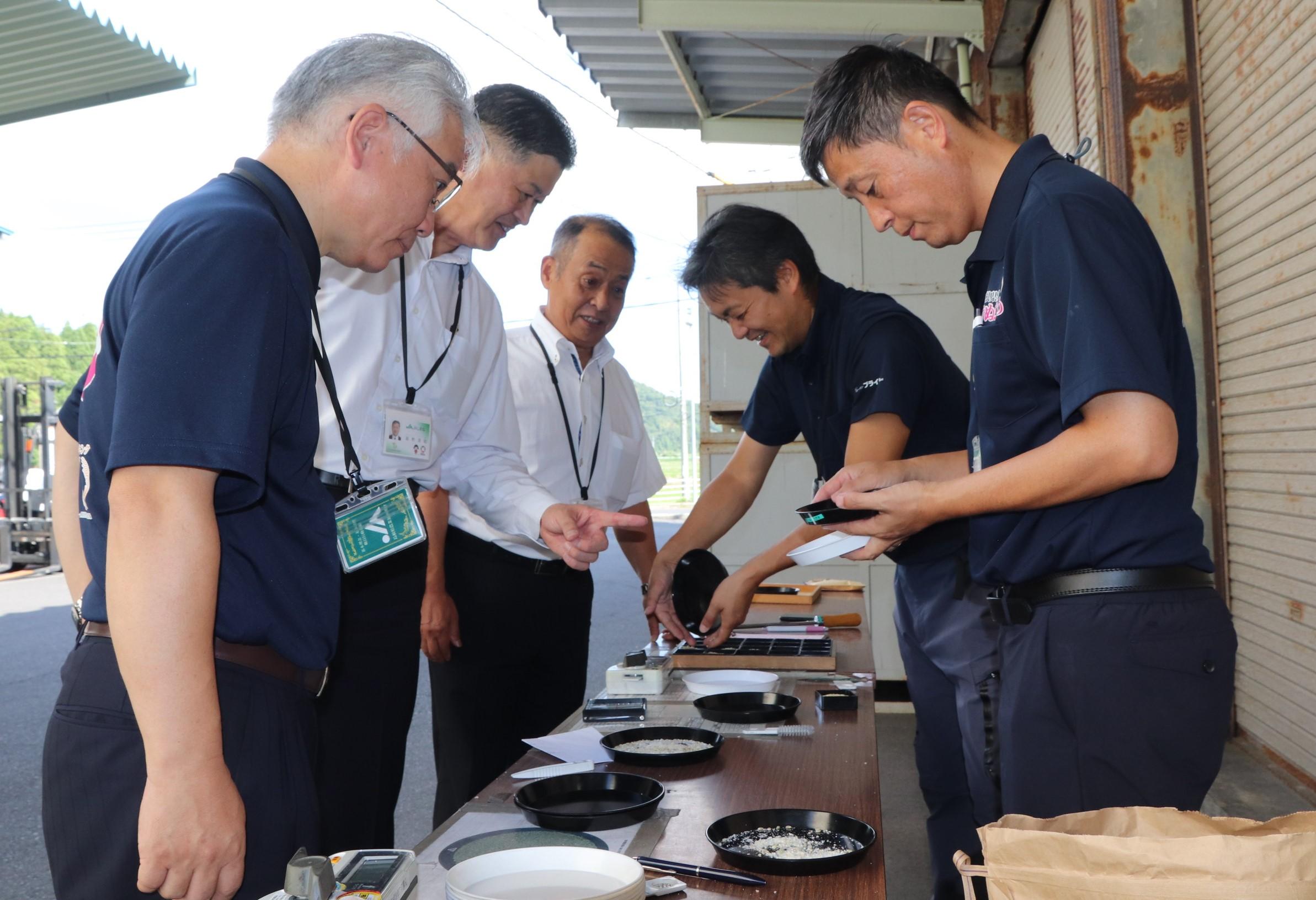 注意深く米を観察する検査員と役員ら.JPG