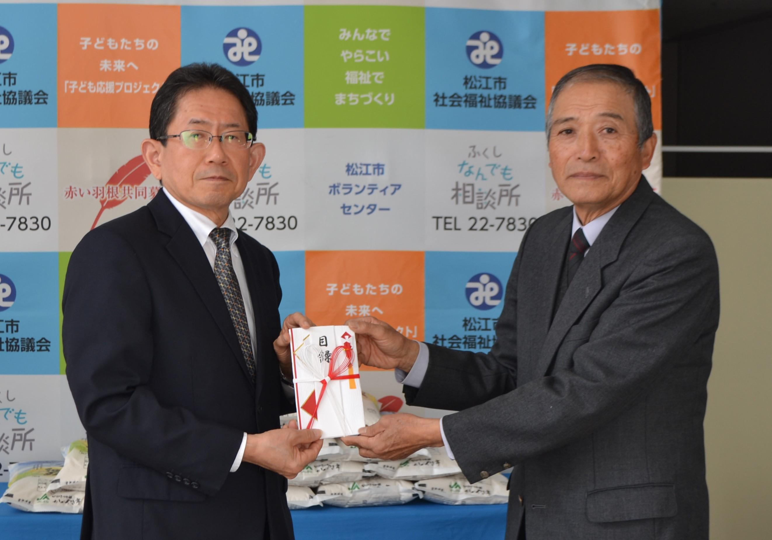 米を受け取る兼折功一専務理事(左)と前田会長(右).JPG