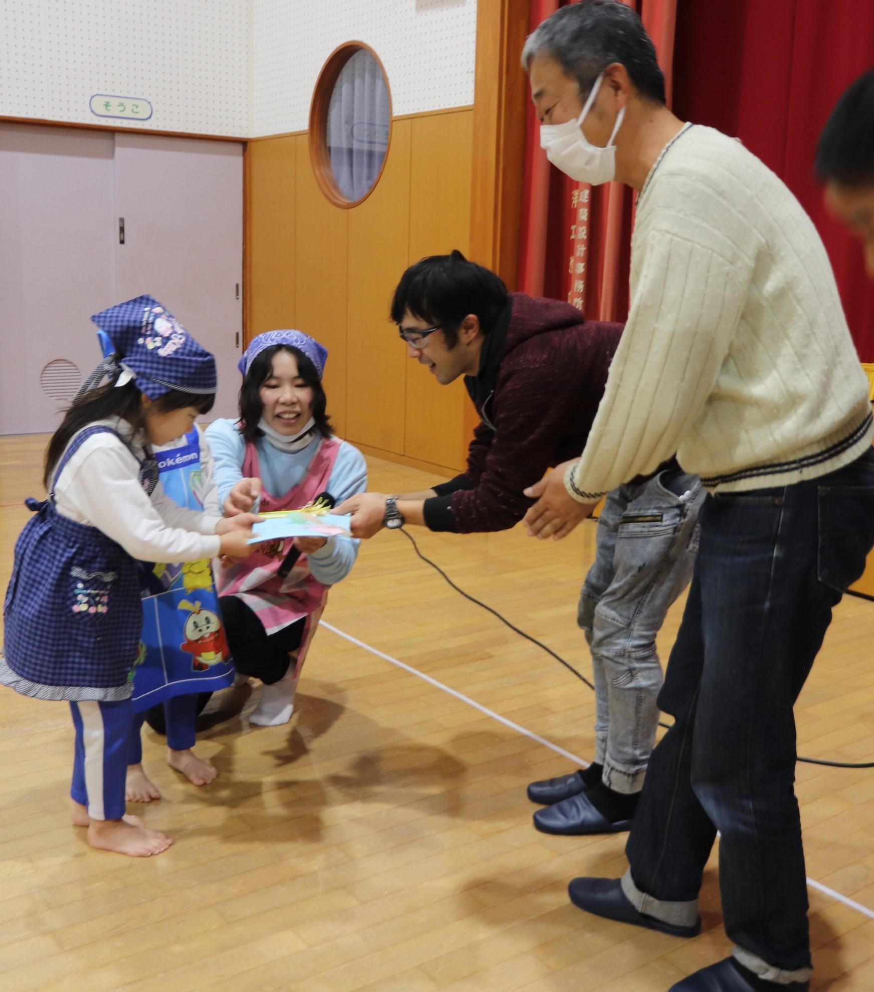 園児たちからプレゼントを受け取る上山根委員長（右から２番目）と野津顧問（右端）２.JPG